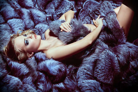 Gorgeous sexy woman lies in expensive mauve fox fur coats. Fur coat fashion. Luxurious lifestyle.の写真素材