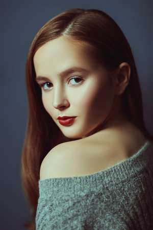 Portrait of young attractive girl in pullover against the blue wall. Fashion studio shot. Copy space.の写真素材
