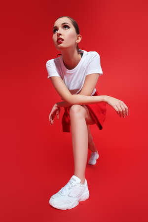 Sportswear fashion. Beautiful athletic girl model posing in modern sportswear on a red background at studio.の写真素材