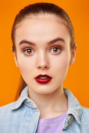 Portrait of a pretty emotional girl in jeans jacket posing on a yellow background. Beauty, fashion....