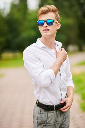 Handsome young man walking in the park and smiling. Summer fashion. Summer holidays and vacation.の写真素材