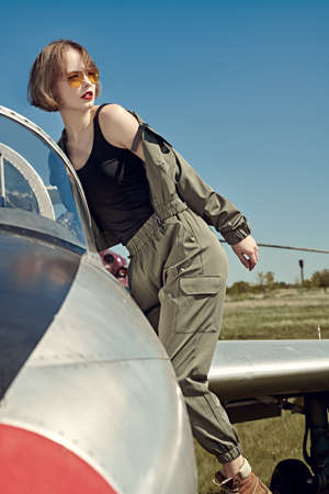 Portrait of a beautiful girl pilot sits in her fighter airplane at the airfield.の写真素材