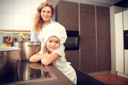 Funny daughter and her mother cook dinner together. Happy family. Healthy eating.の写真素材