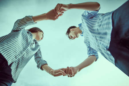 Happy romantic couple in love holding hands against blue sky. People in love. Summertime.の写真素材