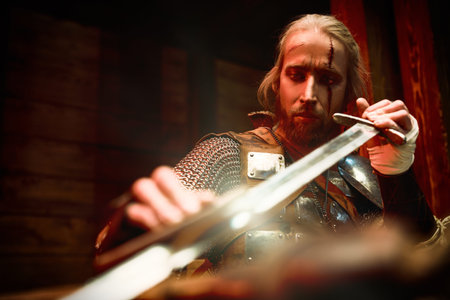 Portrait of a brave medieval warrior in armor looking at his sword. The Witcher man.