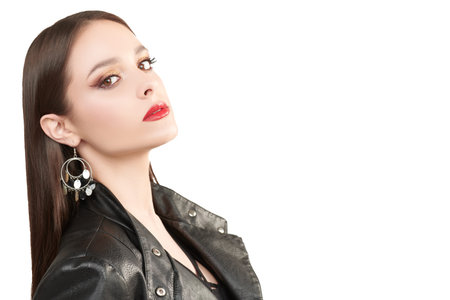 Fashion shot. Portrait of a beautiful brunette girl posing in black leather jacket on a gray...