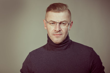 Portrait of a serious mature man in elegant glasses on a gray background. Businessman portrait. Copy...