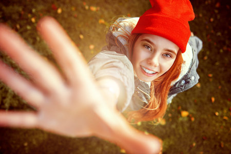 Happy child girl in a beautiful autumn park holds out her hands to the camera and smiles.の写真素材