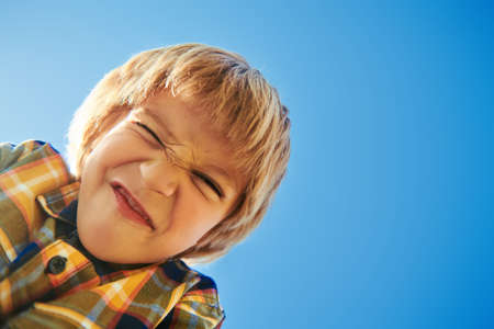 Cute little boy smiling against the blue sky. Retro style. Children's fashion. Autumn and summer season.の写真素材