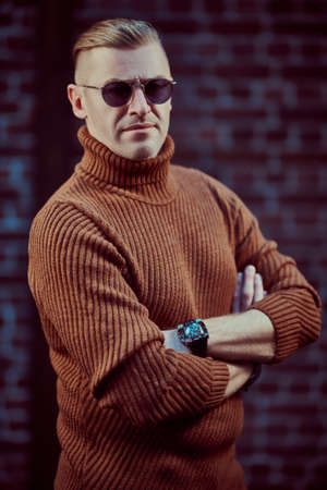 Portrait of a handsome mature man in sunglasses on a brick wall background. Optics style. Men's beauty, fashion.の写真素材