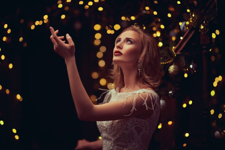 Christmas and New Year magic. Charming happy young woman in a festive evening dress and with...