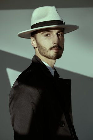 Portrait of a modern businessman. Handsome man in elegant black suit, white shirt and white hat...