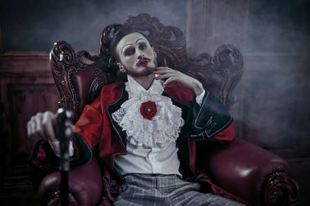 Art, history and fashion. Sophisticated young man with make-up and clothes in the style of the Rococo and Baroque eras in a rich vintage interior.の写真素材