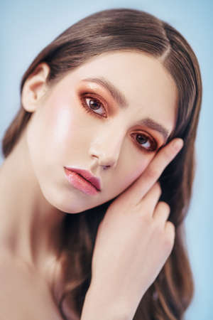 Make-up and cosmetics. Close-up portrait of a beautiful girl with brown make-up on light purple background.の写真素材