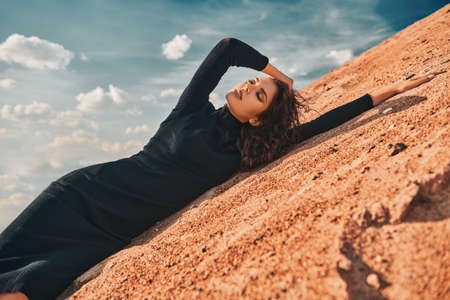 Stunning fashionable woman posing in elegant black dress in the desert.の写真素材