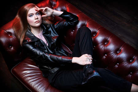 Fashionable female model posing in stylish black leather jacket in a luxurious interior. Nightclub party.の写真素材