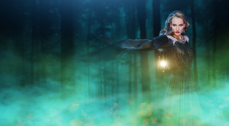 Magic Halloween. Enchanting young woman witch conjures in a dark night forest. Copy space.