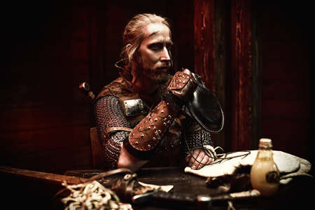 A medieval warrior in armor and with weapons is resting in the inn. Stage portrait. The Witcher man.の写真素材