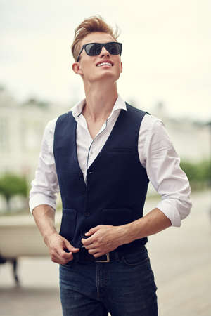 Handsome young man is smiling walking on the city. Summer fashion. Summer holidays and vacation.の写真素材