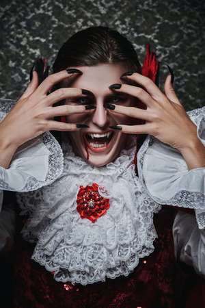 The vampire man covers his face with his hands from the sunlight, he hides in an old castle. Halloween.の写真素材