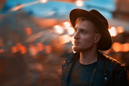 Life in big city. Modern young man walks on the street of a big night city. Hipster style.の写真素材