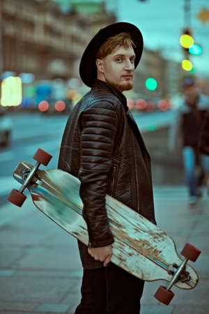 Modern young man hipster walking down the street of a big city with a lorgboard. Active lifestyle.の写真素材