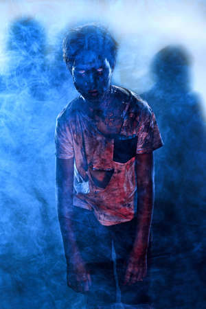 Halloween, horror movie. Portrait of a scary zombie boy teenager in smoke.の写真素材