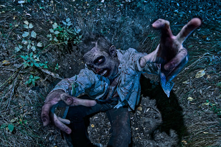 Zombie climbs out of the grave in the night cemetery. Halloween Horror.