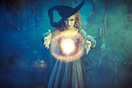 Halloween magic. Enchanting young witch conjures in an old castle. Fairy tales.の写真素材