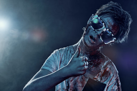 Halloween zombie boy teenager wearing party sunglasses. Halloween party. Copy space.