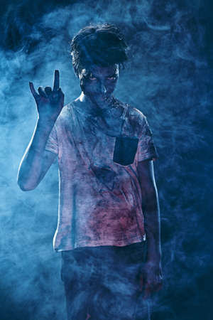 Halloween, horror movie. Portrait of a scary zombie boy teenager in smoke.の写真素材