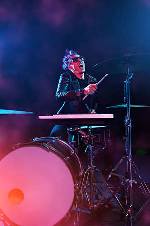 A crazy man is playing the drums in a dark room. Party, disco. Musical instrument.の写真素材