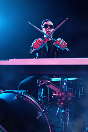 A crazy man is playing the drums in a dark room. Party, disco. Musical instrument.の写真素材