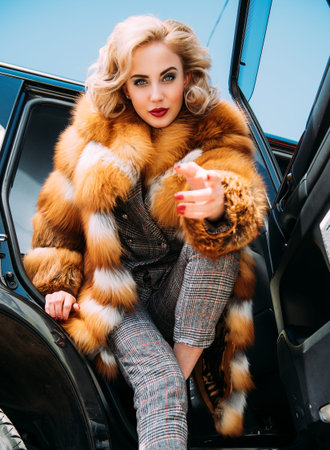 A portrait of a gorgeous blonde lady posing in a car. Car, fashion, beauty, chic.