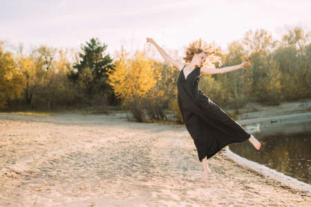 A beautiful young girl is posing outside in a black dress in motion. Fashion concept.の写真素材