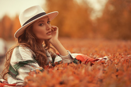 Autumn beauty woman. Portrait of a beautiful young woman in elegant hat in an autumn park, falling...