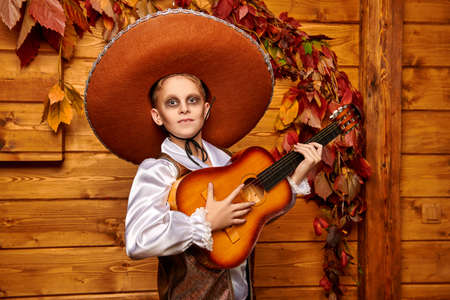 Sugar skull child boy plays the guitar over wooden background. Dia de los muertos. Day of The Dead. Halloween.の写真素材