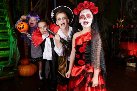 Halloween. Funny scared kids in carnival costumes wander through the old castle on Halloween.の写真素材