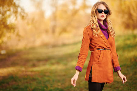 Beautiful young woman walks through the autumn park. Autumn beauty, fashion.の写真素材