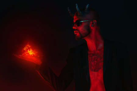 A portrait of a bad demon in sunglasses with fire in hand. Horror movie, nightmare. Halloween.