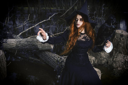 A portrait of an angry witch with a black raven outdoor. Magic, dark force, spell.