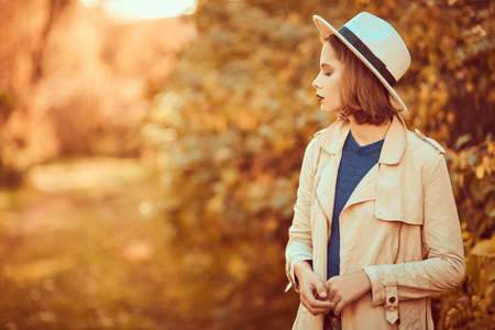 Pretty modern girl in casual clothes walks through the autumn city park. Seasonal style, autumn beauty, fashion.の写真素材