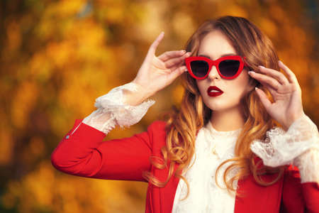 Elegant young woman in sunglasses posing in a beautiful autumn park. Beauty, fashion.の写真素材