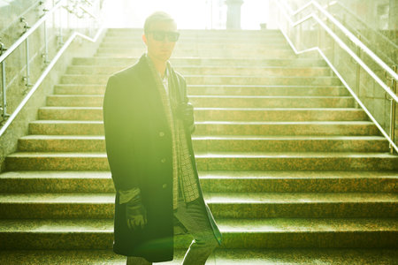 A man walks up the stairs from an underpass lit by the sun on an autumn day. Life in the city.