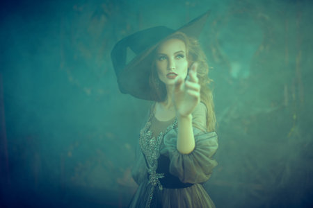 Halloween magic. Enchanting young witch conjures in smoke old castle. Fairy tales.