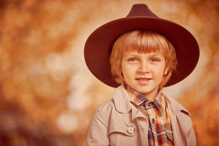 Funny romantic boy in hat is smiling in a beautiful autumn park. Children's fashion. Retro style.の写真素材