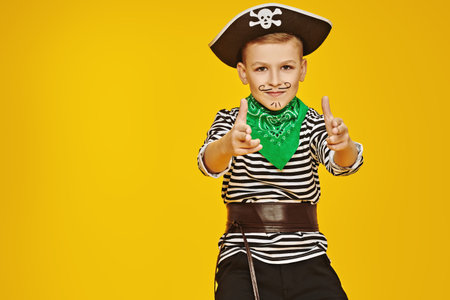 Happy Halloween! Cool cheerful boy in a pirate costume posing on a yellow background at the studio....