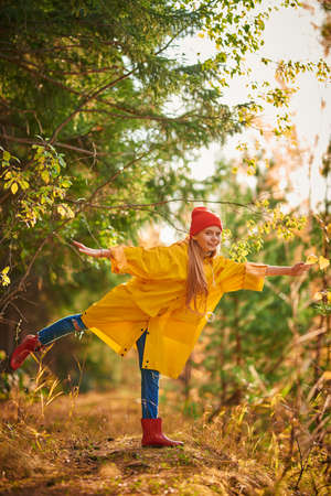 Cute smiling girl is posing in a beautiful autumn forest. Autumn season. Full length portrait.の写真素材