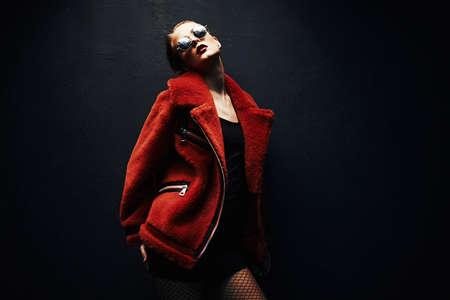 Gorgeous woman posing in luxurious fur coat on black background in the light. Fashion, beauty. Studio shot.の写真素材