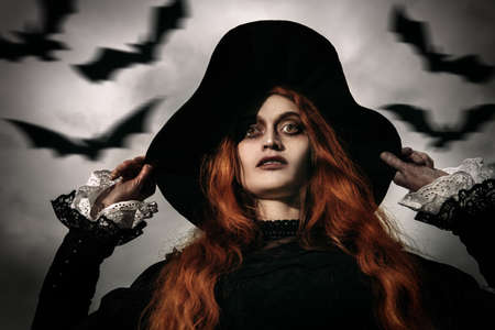 A portrait of an angry witch against the background of flying bats in the sky. Halloween.の写真素材
